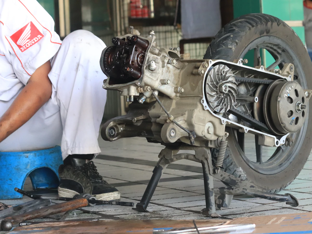 Mechanic servicing the exposed transmission of a scooter