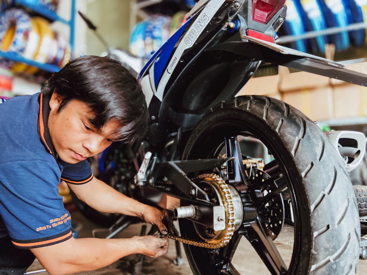 Mechanic performing maintenance near a motorcycle rear wheel