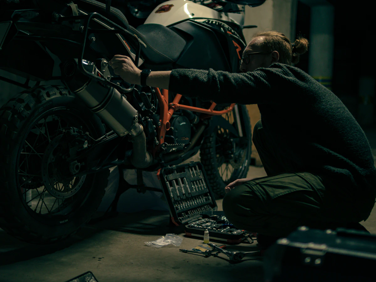 Mechanic servicing a motorcycle rear assembly in a workshop