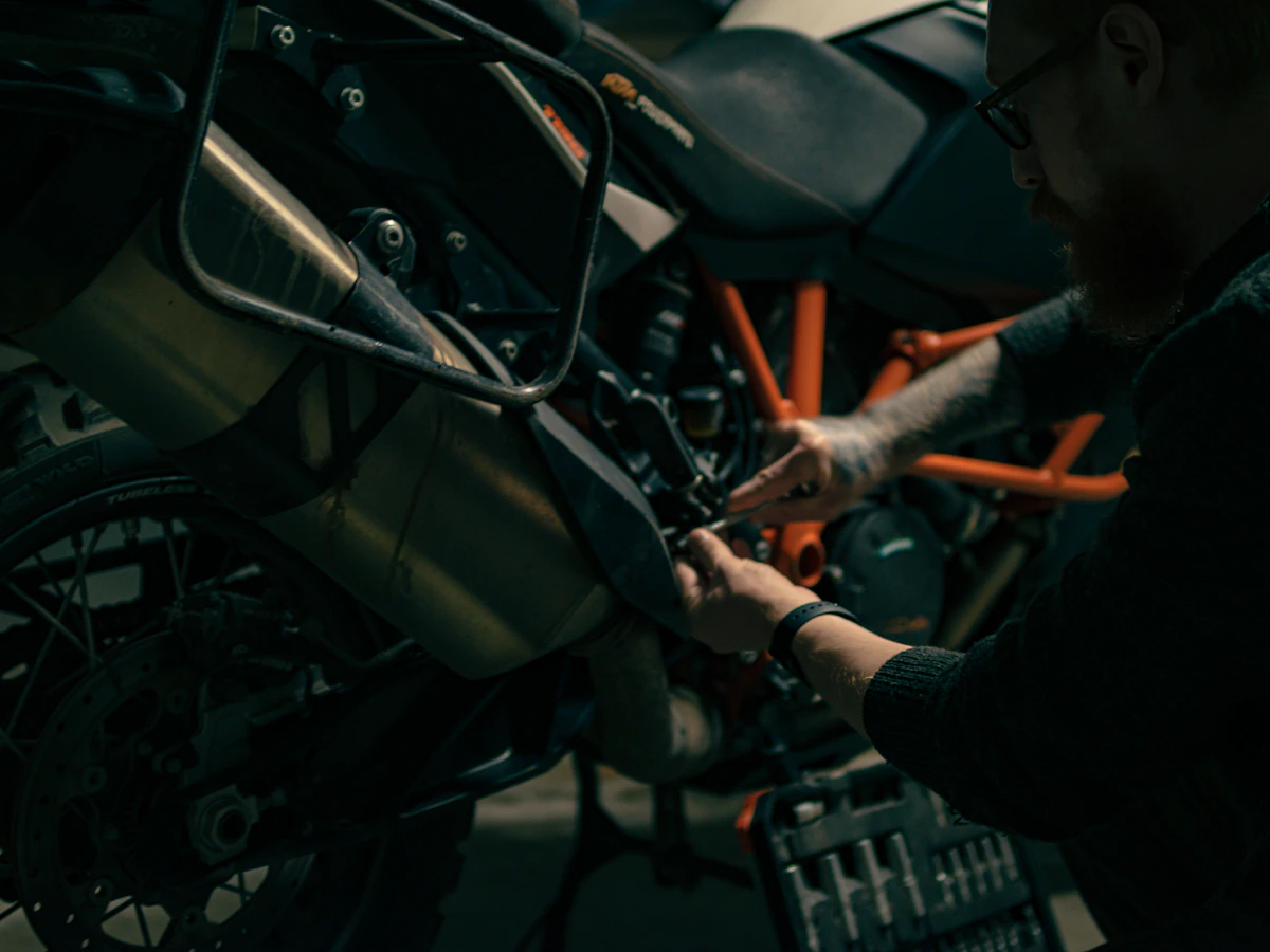 Technician working on motorcycle components in a dark workshop