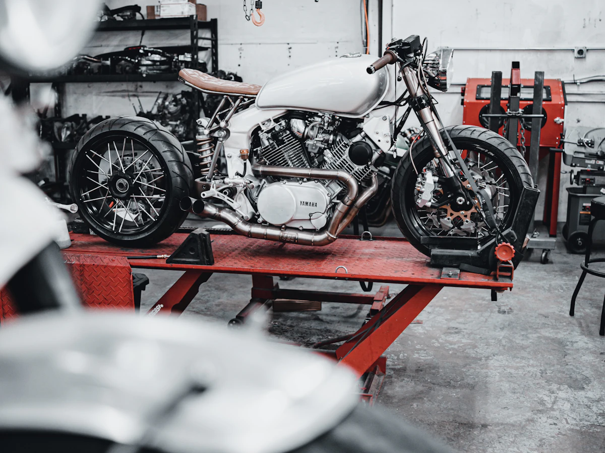 White motorcycle positioned on a service lift inside a workshop